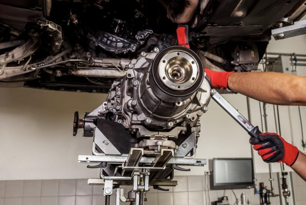 Mecánico apretando con una llave un componente de la caja de cambios de un coche en el taller