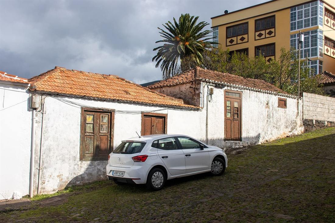 Seat Ibiza blanco aparcado junto a una casa antigua